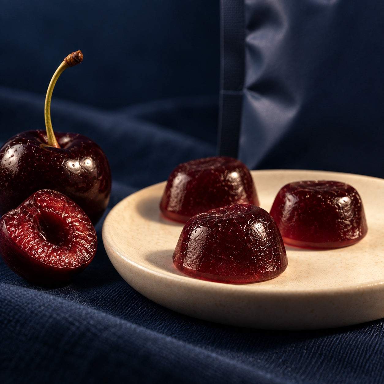 Deep cherry-colored pillow gummies on a cream dish